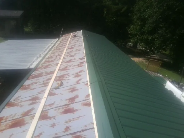 Old rusted panels beside newly installed green metal roofing — Wind Damage Roof Repair by Roofing Brothers in Kings Mountain
