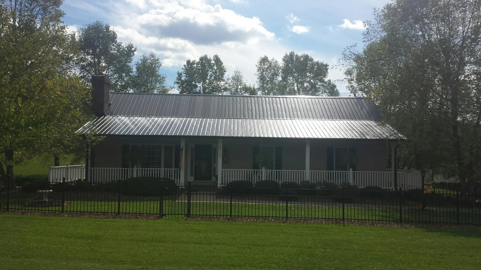 Gray metal roof on a brick ranch with a full width front porch — Gutter Guard Installation work by our crew in Kings Mountain